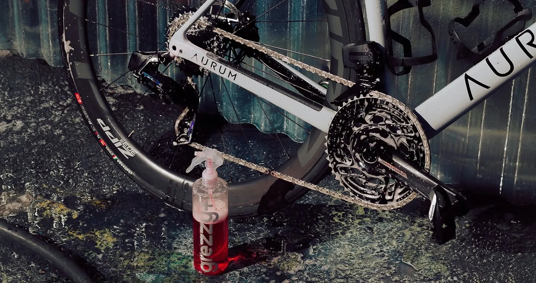 Freshly cleaned road bike drivetrain with a Grezzy+ cleaner bottle by the chainring